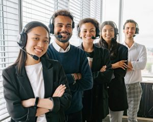 Diverse group of call center professionals wearing headsets, standing confidently in an office.